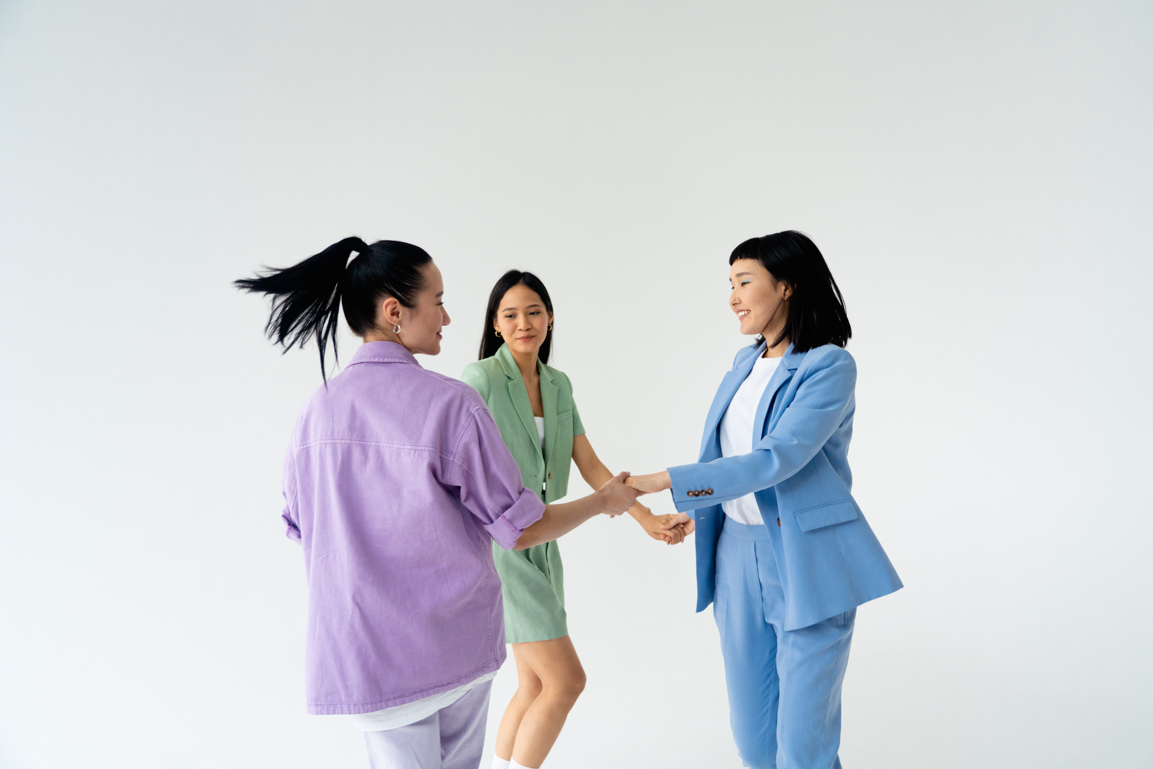 Women in Pastel Color Outfit Playing Together while Holding Each Others Hands